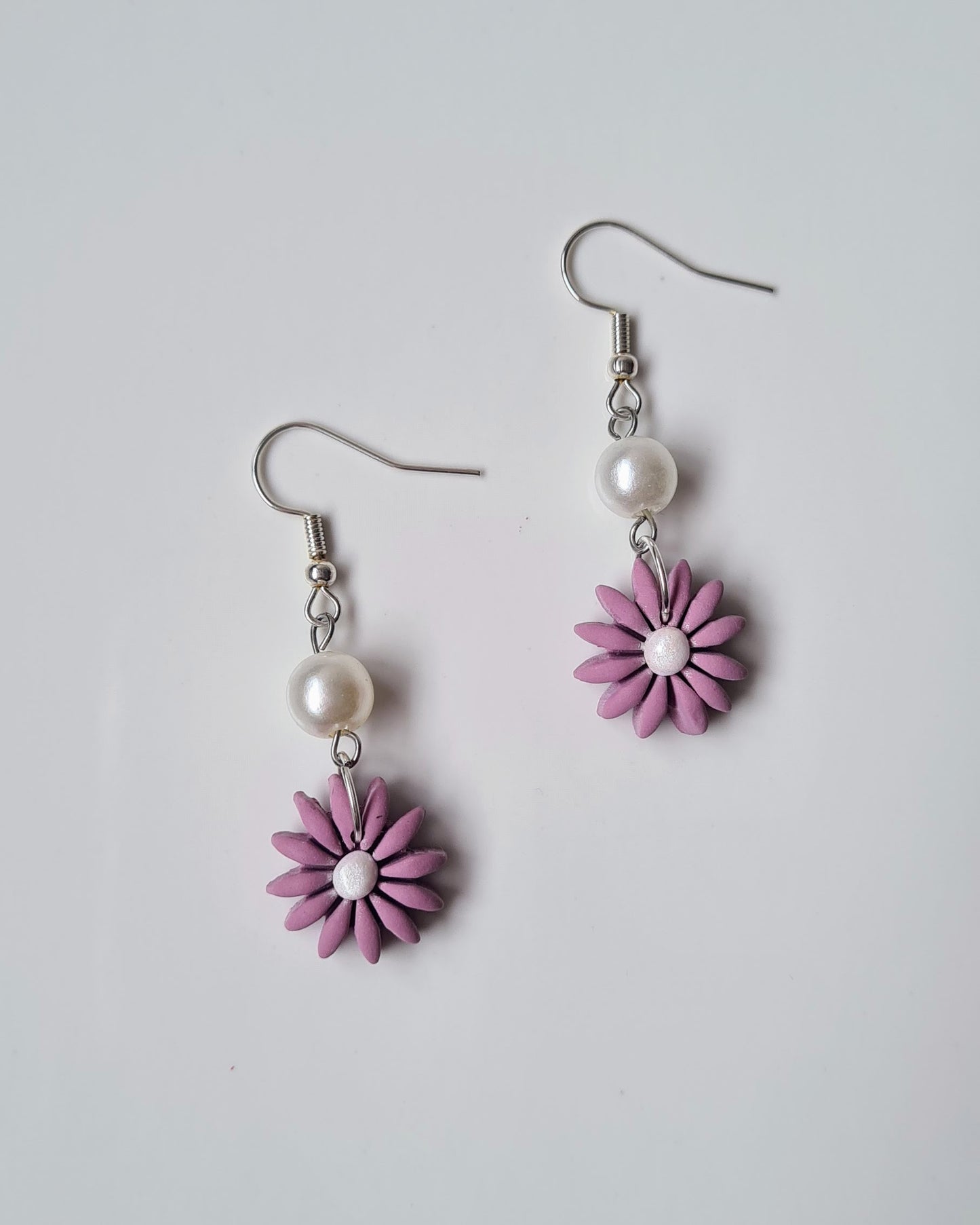 Pair of Lavender flower-shaped earrings with pearl centres on a light grey background