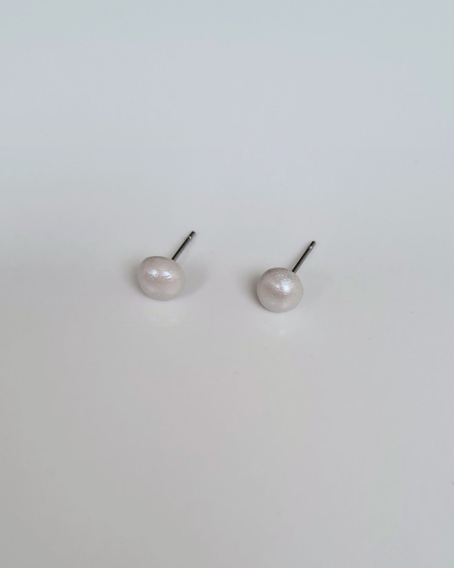 Pair of pearl stud earrings on a light gray background