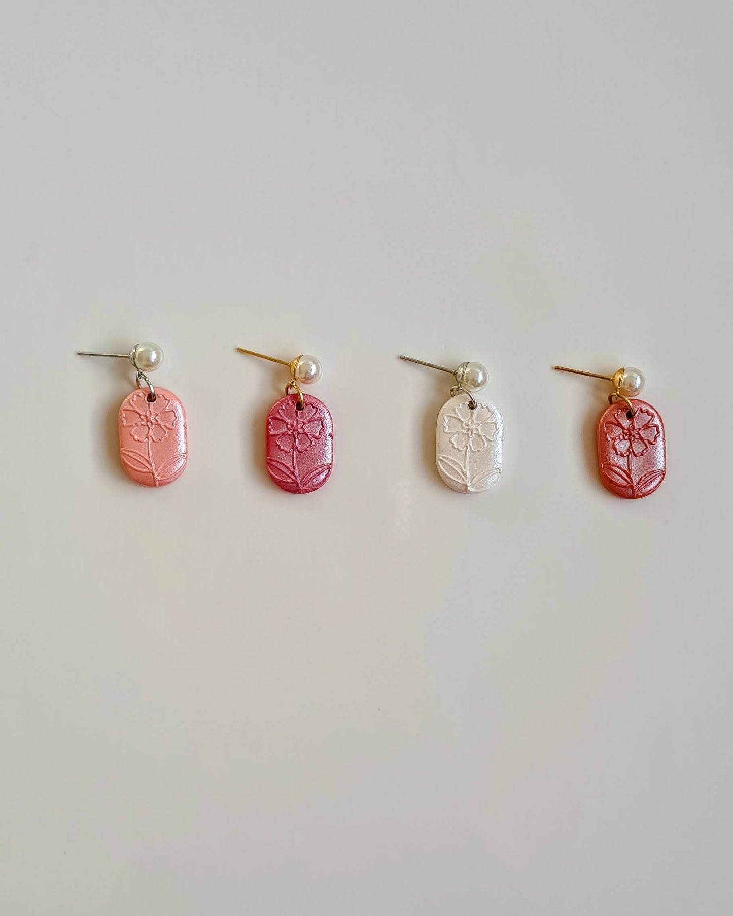Four pairs of earrings on a light gray background