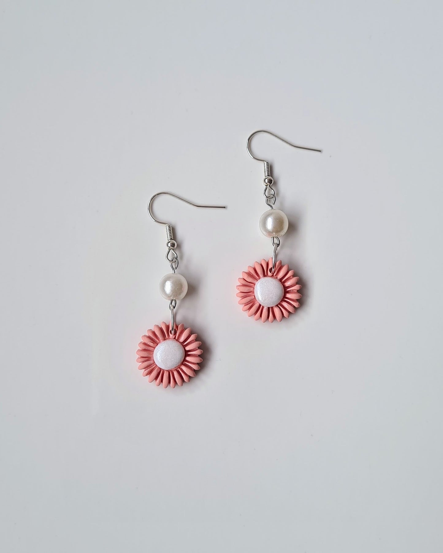 Pair of peach drop earrings on a light grey background