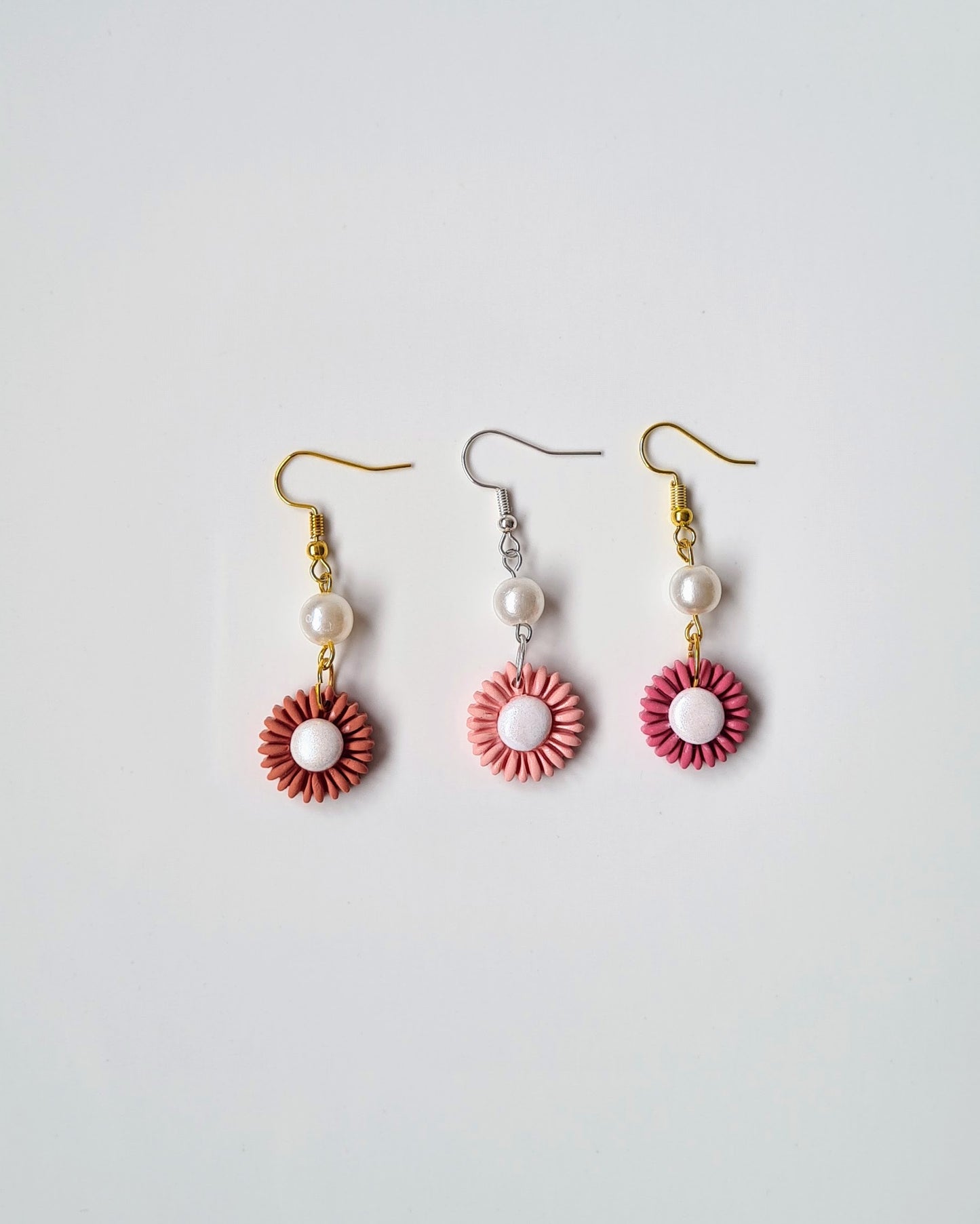 Pearflower drop earrings in three floral tones with pearl accents on a light grey background