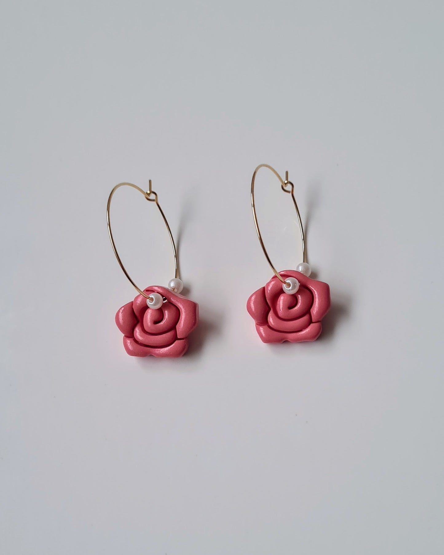 Coral rose-shaped earrings on a light gray background