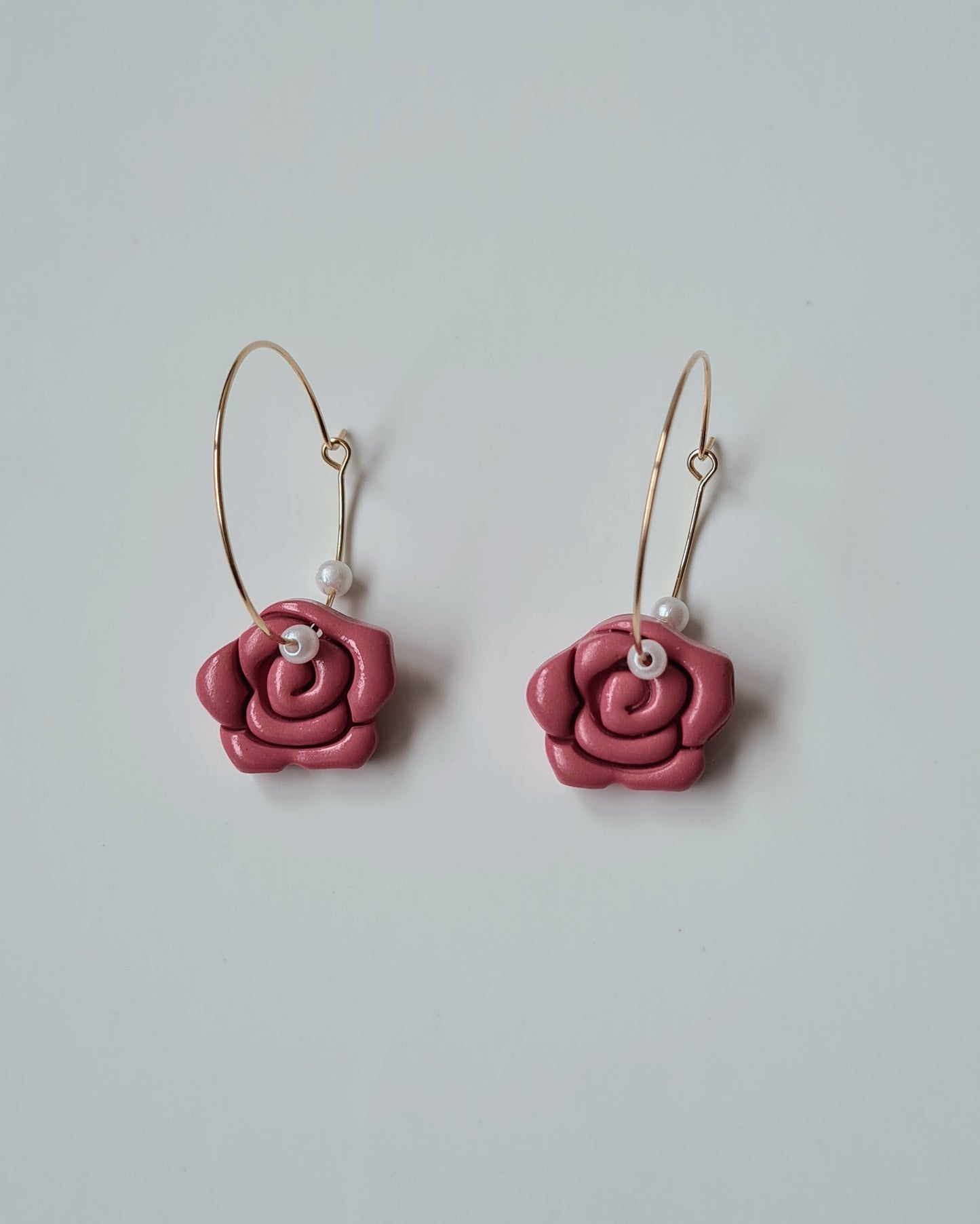 Red rose-shaped earrings on a light grey background