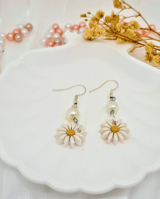 Floral earrings on a white dish with dried flowers