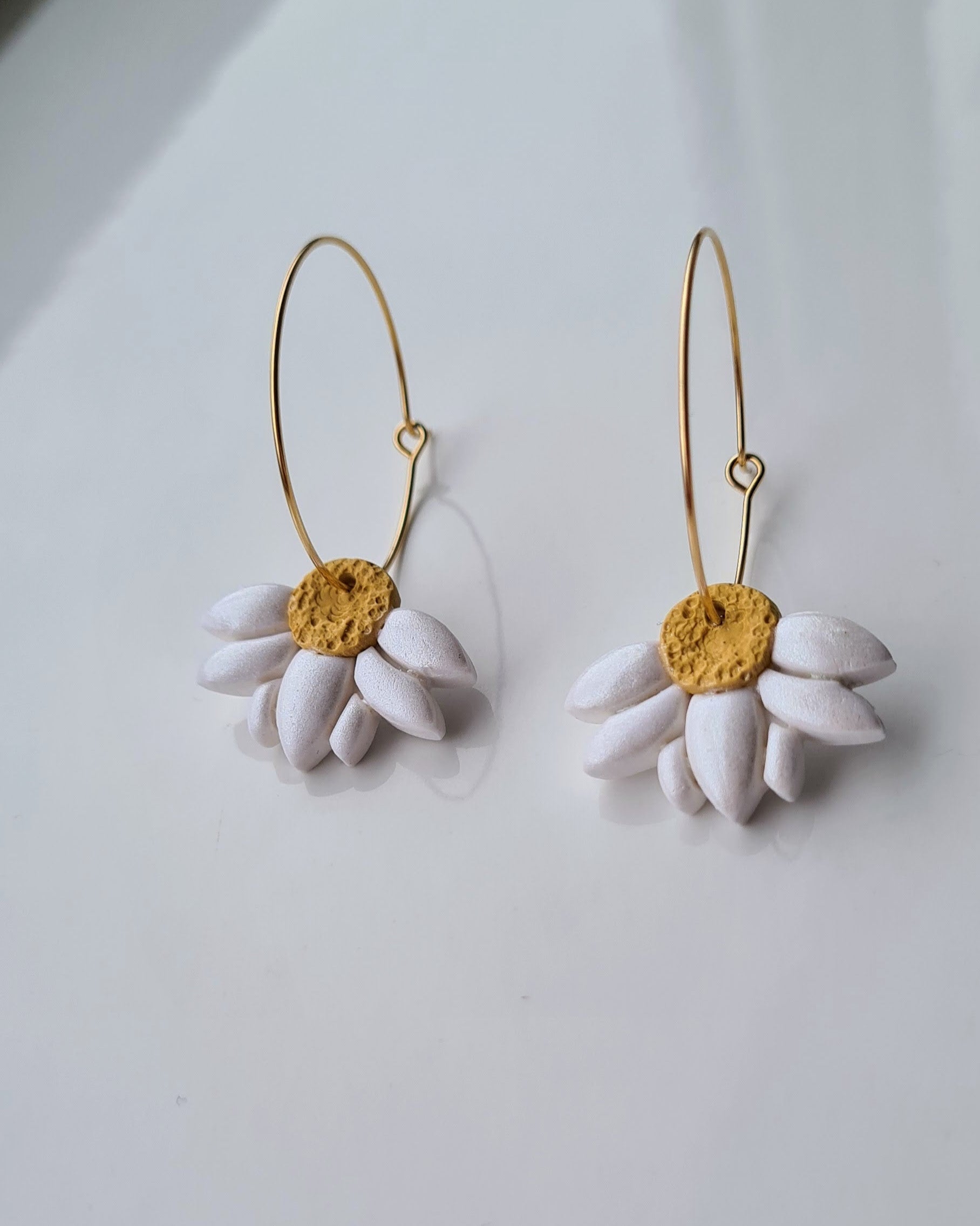 White Daisy hoop earrings with yellow centers on a white background