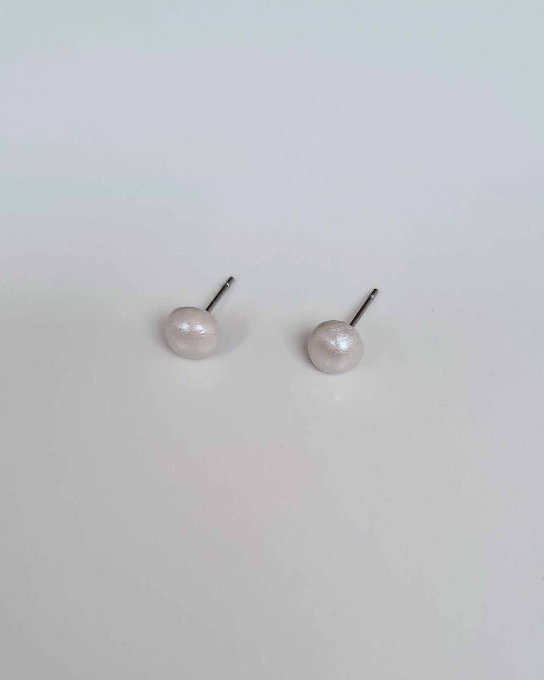 Pair of pearl stud earrings on a light gray background