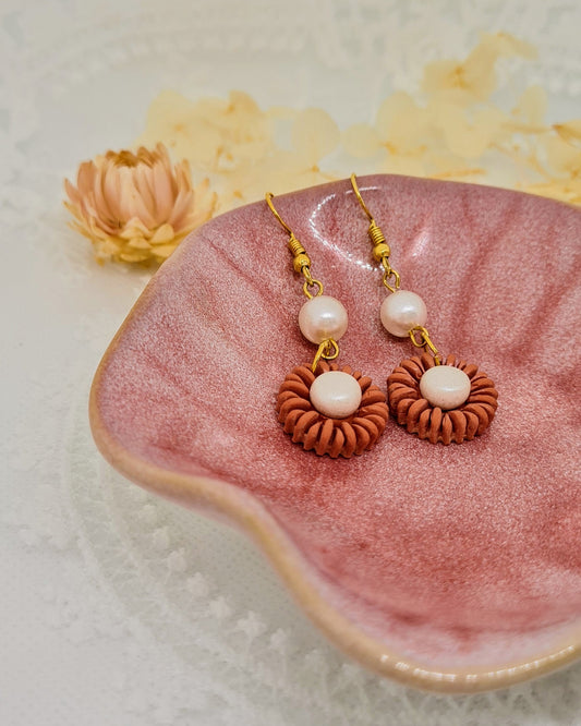 Pair of earrings with pearls on a pink shell against a light background