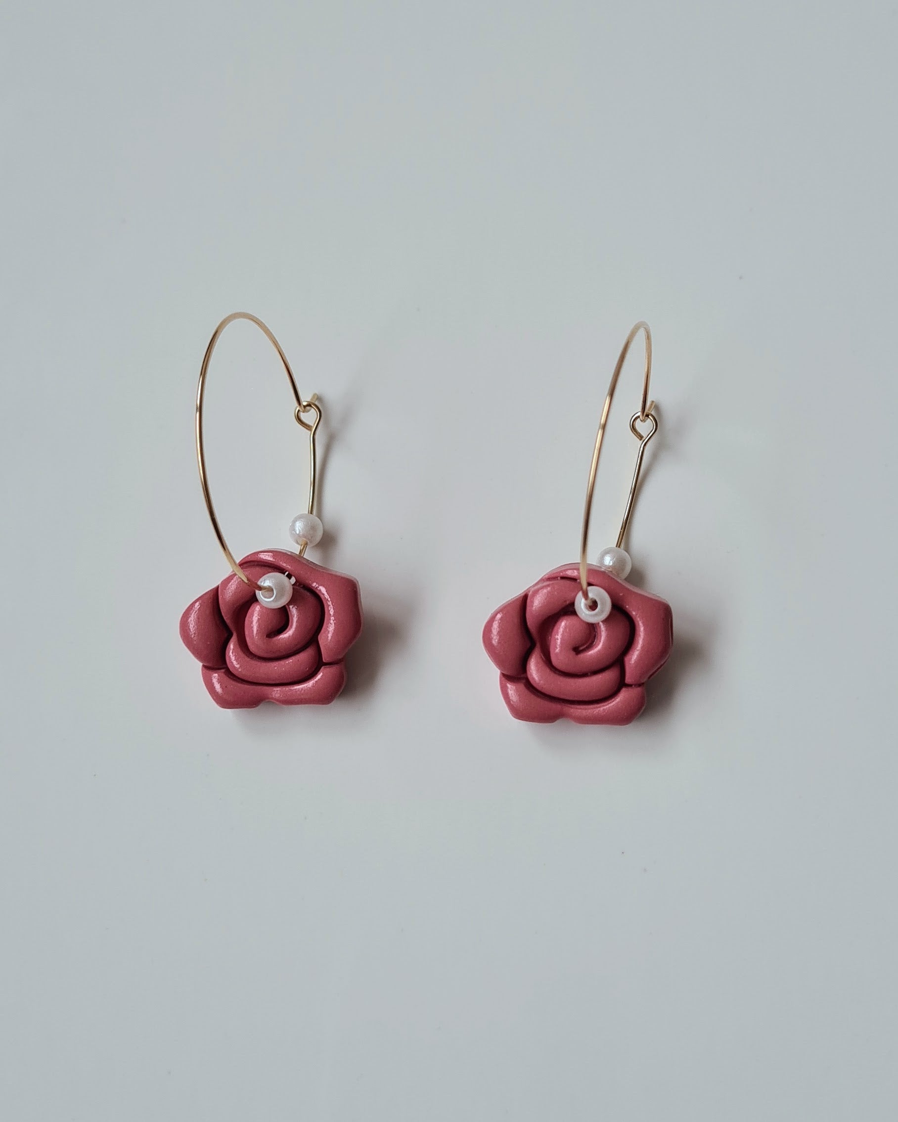 Red rose-shaped earrings on a light grey background