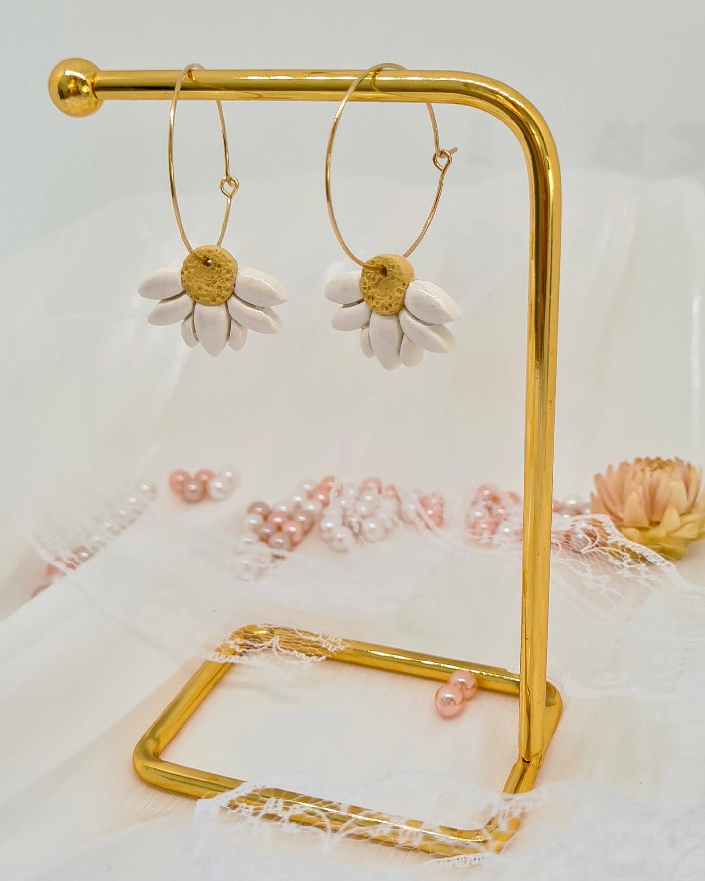 Gold hoop earrings on a gold stand with a floral background
