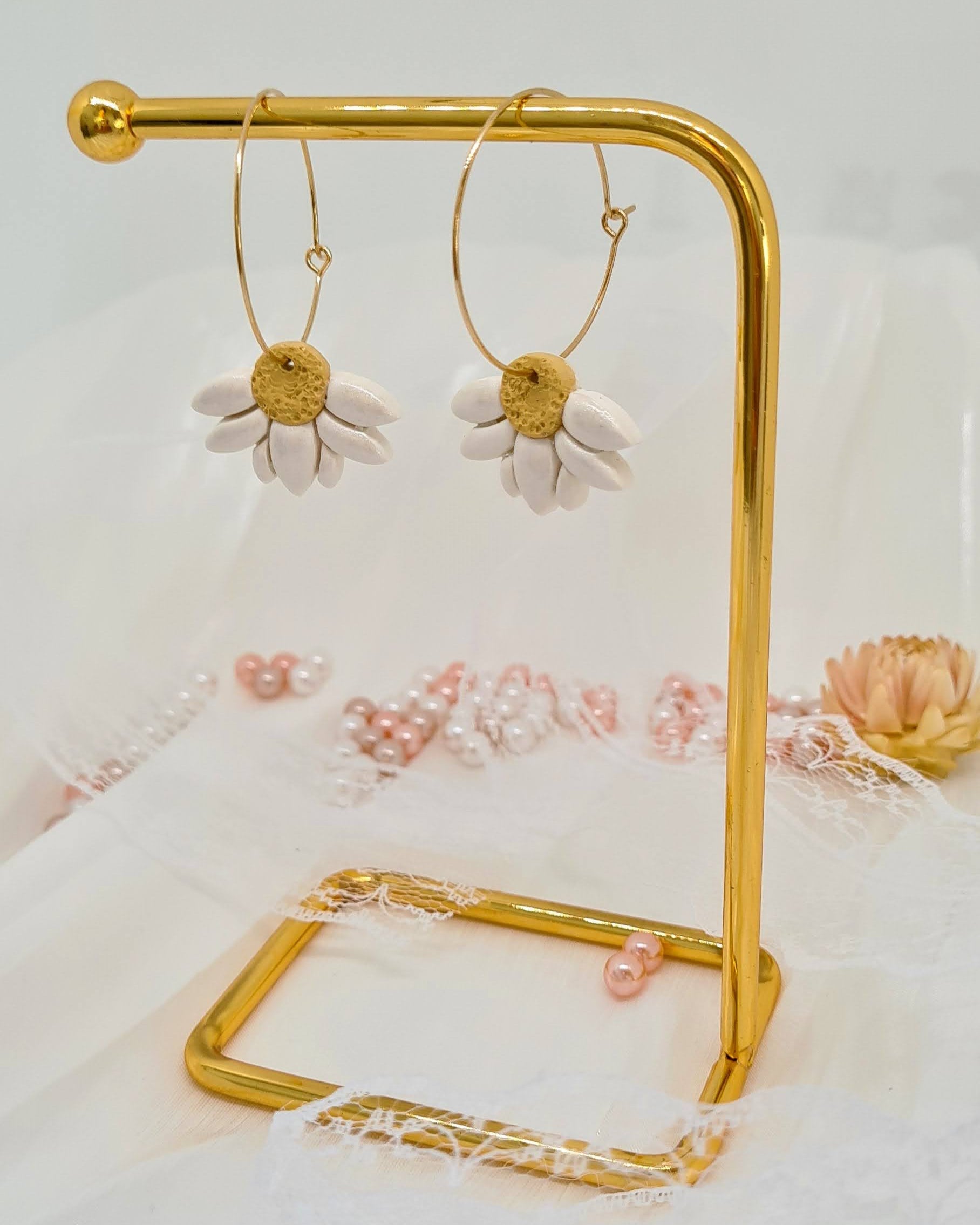 Gold hoop earrings on a gold stand with a floral background