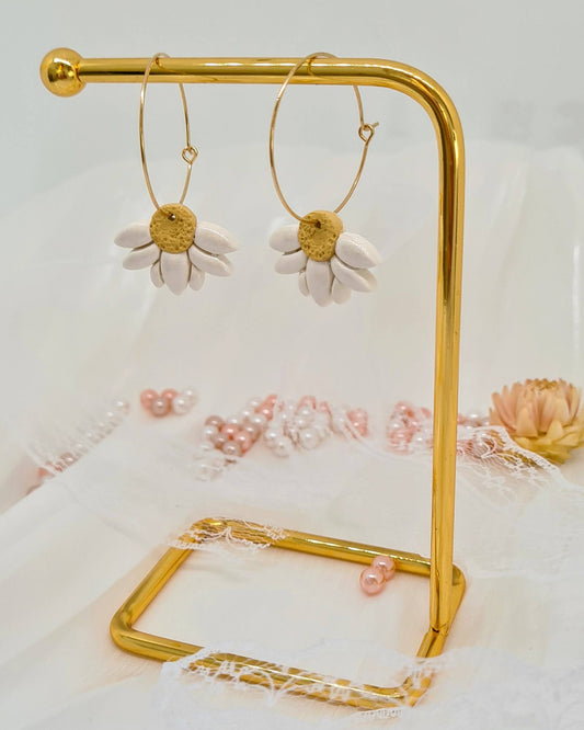 Gold hoop earrings on a gold stand with a floral background